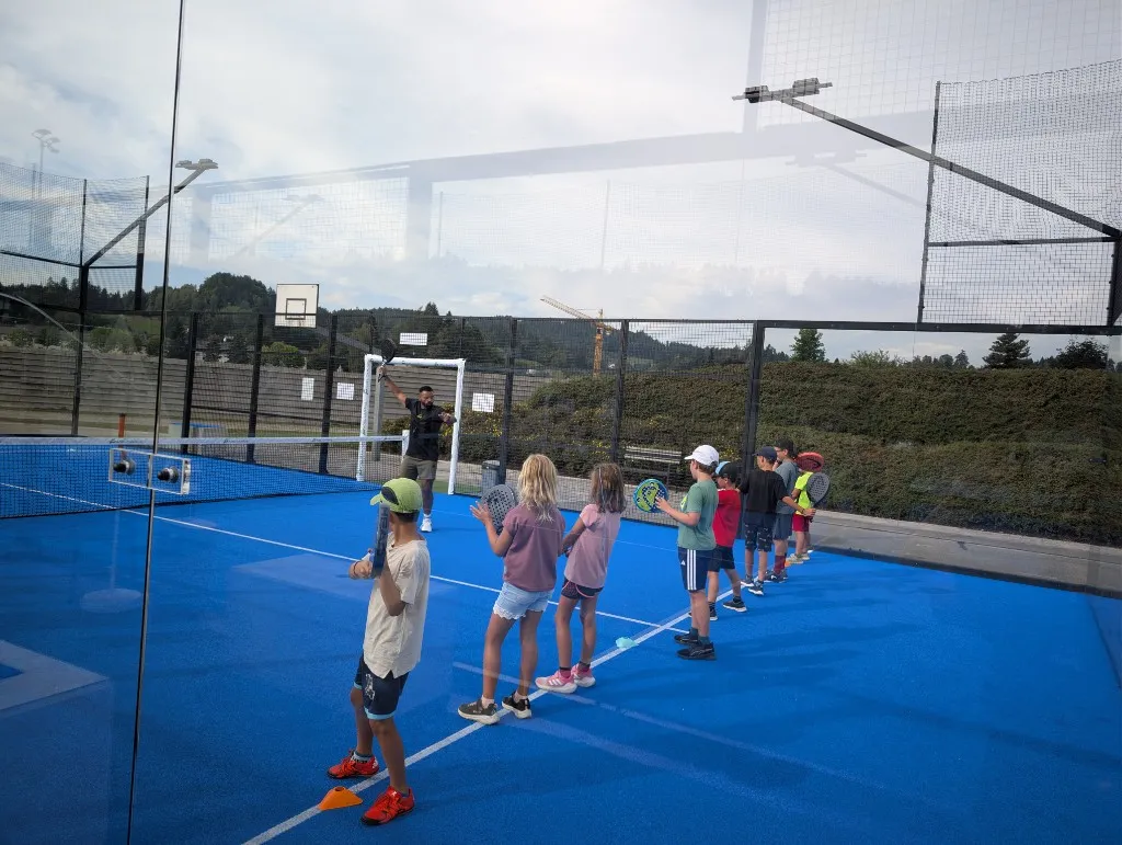Trainer zeigt Kindern die Technik mit Ball am Court